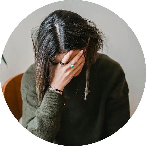 Person holding their head in distress to show symptoms related to hormonal imbalance.